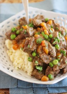 a white plate topped with meat and vegetables on top of mashed cauliflower