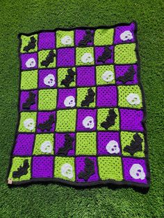 a crocheted blanket with skulls and bones on it is laying on the grass