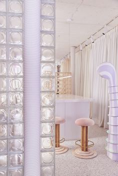 the interior of a store with stools and glass blocks on the wall behind them