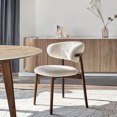 a white chair sitting next to a wooden table on top of a carpeted floor