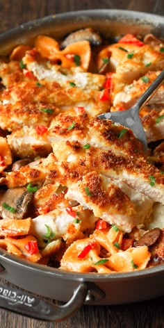 a pan filled with chicken and vegetables on top of a wooden table