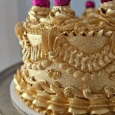 there is a gold cake with pink decorations on it