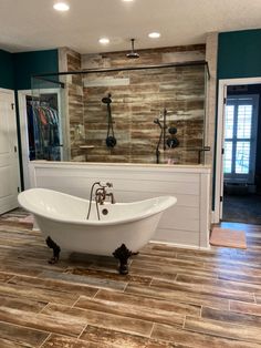 a bath tub sitting on top of a wooden floor next to a walk in shower