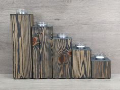 wooden candlesticks stacked on top of each other in front of a wood wall