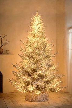 a small white christmas tree in a room with lights on the branches and around it