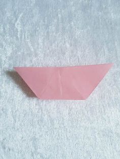 an origami paper boat sitting on top of a white blanket