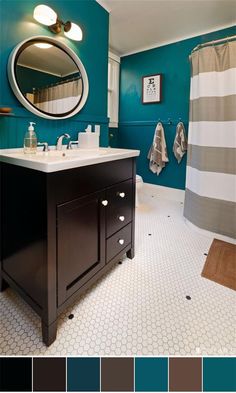 a bathroom with teal walls and white tile flooring, along with a large round mirror on the wall