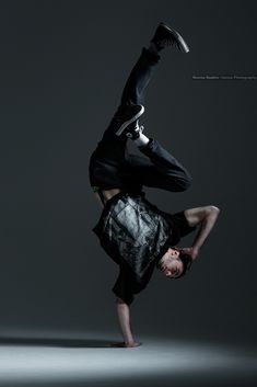 a man doing a handstand in the air with his feet on the ground