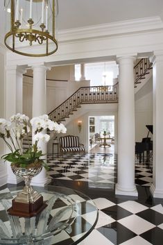 the foyer is decorated with black and white checkered flooring, columns, and vases filled with flowers