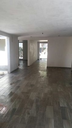 an empty room with wood flooring and white walls in the background is a doorway leading to another room