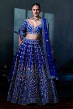 Motifs inspired by arches of royal palaces and regal interpretations of botanical imageries adorn this deep blue silk lehenga. This intricately embroidered creation is embellished additionally with pearl and zari work. Pockets come included. Customisation Available For: Choli sleeves and Choli length Specifications: Style Number: F21R4LCD Model Info: Model height is 5 ft 9 in (175 cms) and is wearing a size S. Measurements:Lehenga Length: 44 Inches Choli Length:14.5 Inches Dupatta Length:110 Inc Indian Bridal Lehangas, Blue Lehnga Dress, Blue Lehngas, Latest Bridal Lehenga 2023, Indian Wedding Bridal Outfits, Blue Bridal Lehenga, Latest Bridal Lehenga, Indian Sari Dress, Reception Lehenga