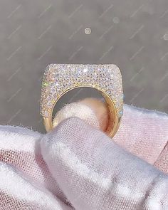 a person wearing a gold ring with white diamonds on it's finger and the top half