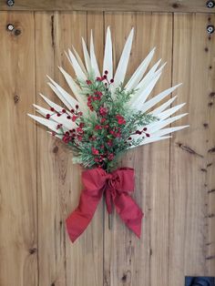 a bunch of flowers that are sitting on a wooden wall with a red ribbon around it