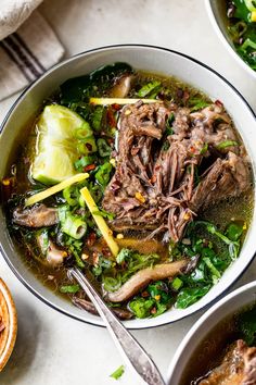 two bowls filled with beef and greens soup