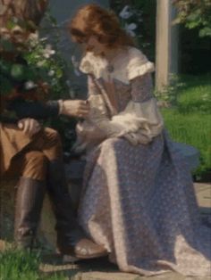 a man and woman dressed in period clothing sitting on a bench