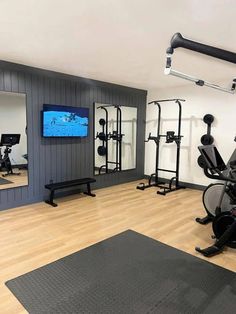 an exercise room with mirrors, treadmills and other equipment in front of a flat screen tv