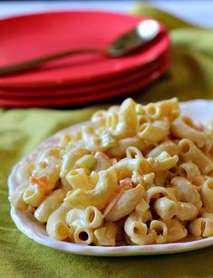 a plate full of macaroni and cheese on a green tablecloth next to red plates