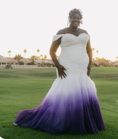 a woman in a purple and white dress standing on the grass