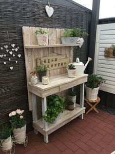 an outdoor area with potted plants and wooden shelves