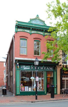 an old fashioned ice cream shop on the corner of a street in front of a red brick building