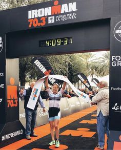 a woman is crossing the finish line with her arms in the air