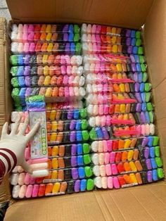 a cardboard box filled with lots of different colored crayons and a hand next to it