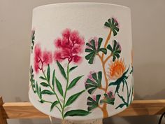 a lamp shade with flowers painted on it and some wires in front of the lampshade