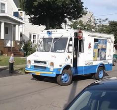 an ice cream truck is parked on the side of the road in front of some houses