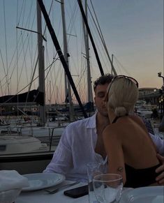 a man and woman sitting at a table in front of sailboats