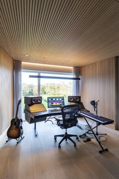 a recording studio with sound equipment and guitar on the floor in front of a large window