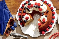 a cake with berries and whipped cream on top is sitting on a white platter