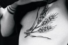 black and white photo of a woman's stomach with flowers on her side tattoo