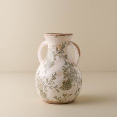 a white and green vase sitting on top of a table