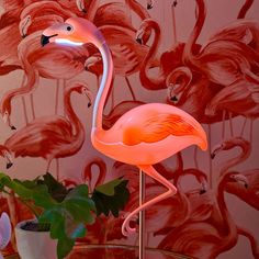 a pink flamingo lamp sitting on top of a table next to a potted plant