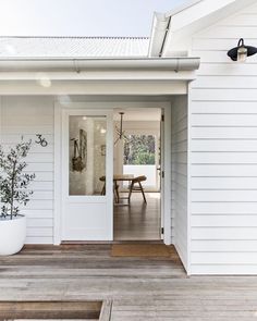 a white house with an open door and potted plant on the front porch area