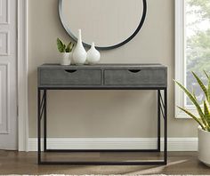 a console table with two vases and a round mirror on the wall behind it