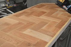 a wooden table top sitting on top of a hard wood floor next to a tool box