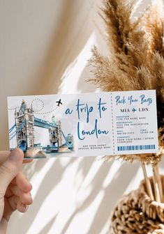 a person holding up a ticket for a trip to london with the tower bridge in the background