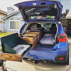 the back end of a blue car with its trunk open and two wooden boxes in it