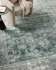 a blue rug with an ornate design on the top and bottom, in front of a couch