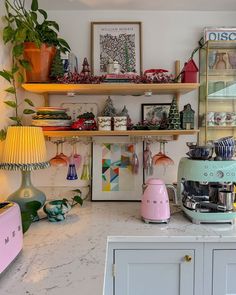 a kitchen counter with various items on it and a pink coffee maker in the middle