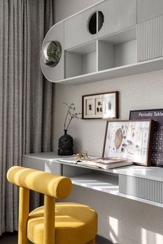 a yellow chair sits in front of a desk with pictures on it and a clock