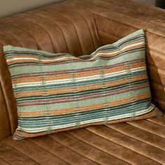 a brown leather couch with a striped pillow on it's back and the seat up