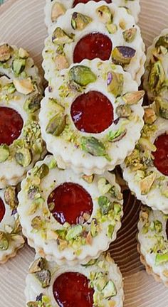 several desserts are arranged on a plate with white frosting and pistachio toppings