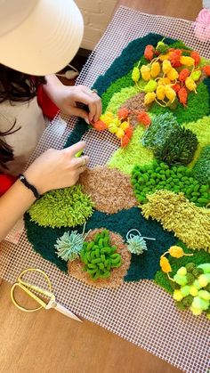 a woman is working on an art project made out of succulents and flowers