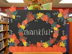 a sign that says, thank you with leaves and pumpkins on it in front of a bookcase