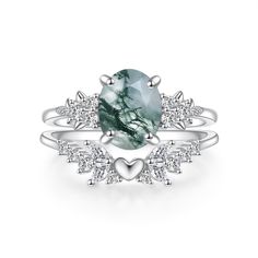 a ring with an oval green stone surrounded by white diamond accents and hearts on the side