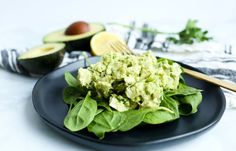 a black plate topped with lettuce and avocado