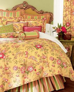 a bed with yellow and pink floral comforter set on top of wooden flooring