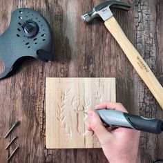 a person carving wood with a hammer and other tools on a wooden table next to it